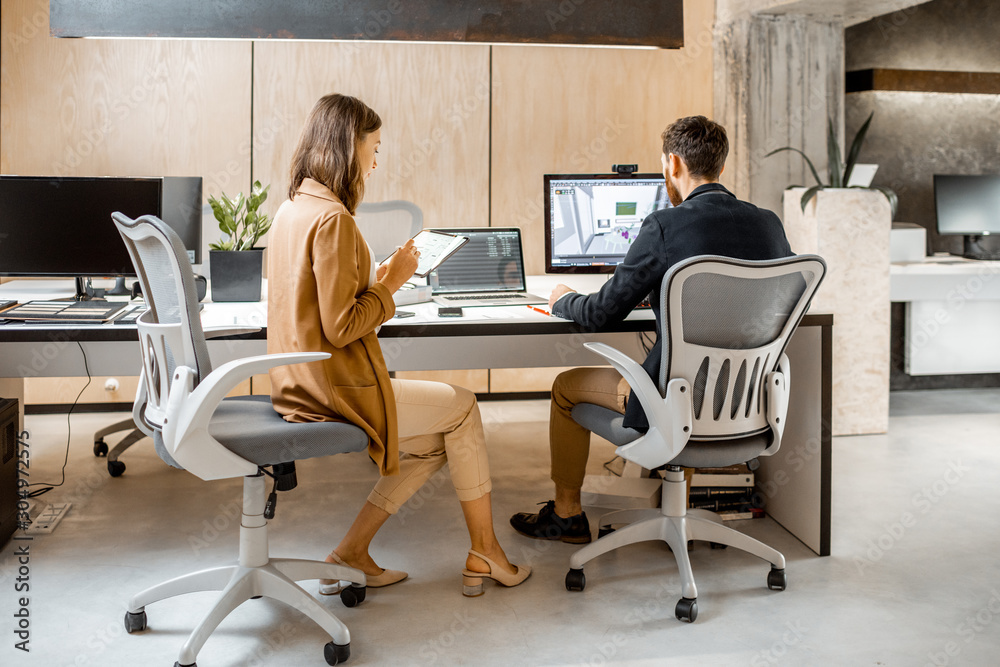 Two creative office employees making interior design on the computer and digital tablet at the moder