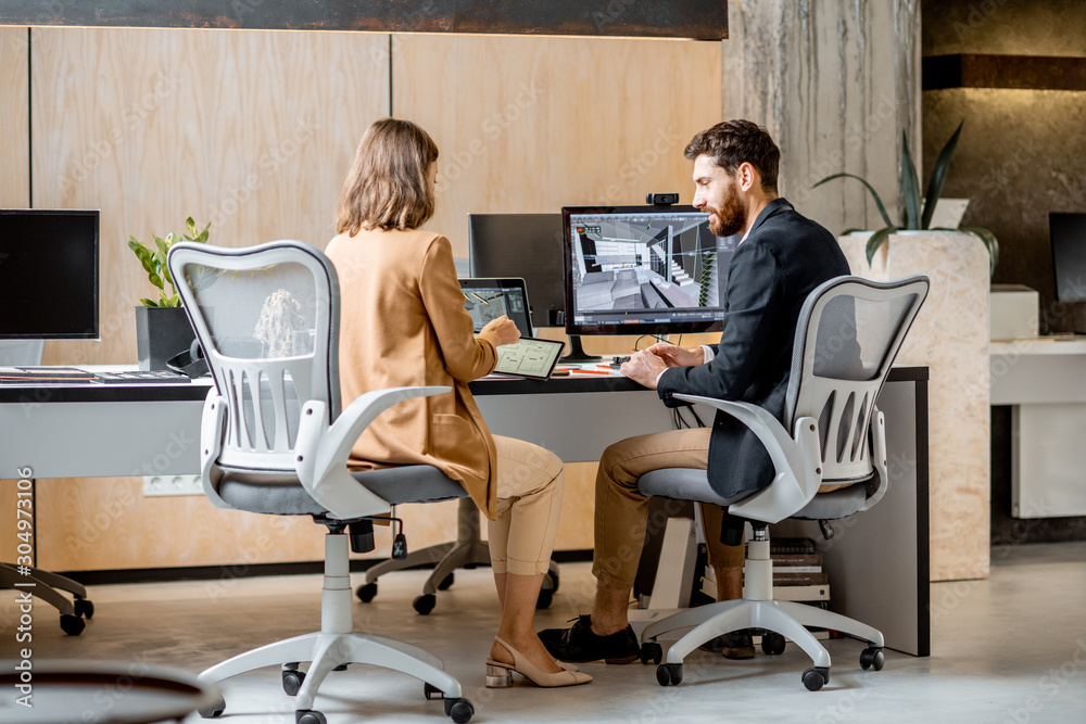 Two creative office employees making interior design on the computer and digital tablet at the moder