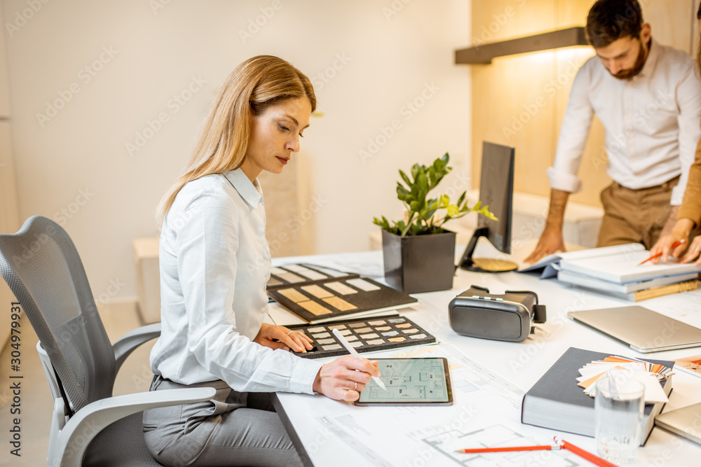 Young employees dressed casually doing some creative work at the large table with computers in the o