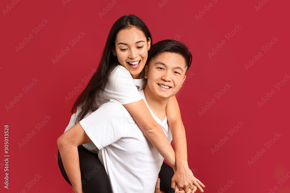 Portrait of happy young Asian couple on color background