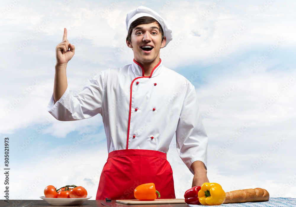 Young male chef standing near cooking table