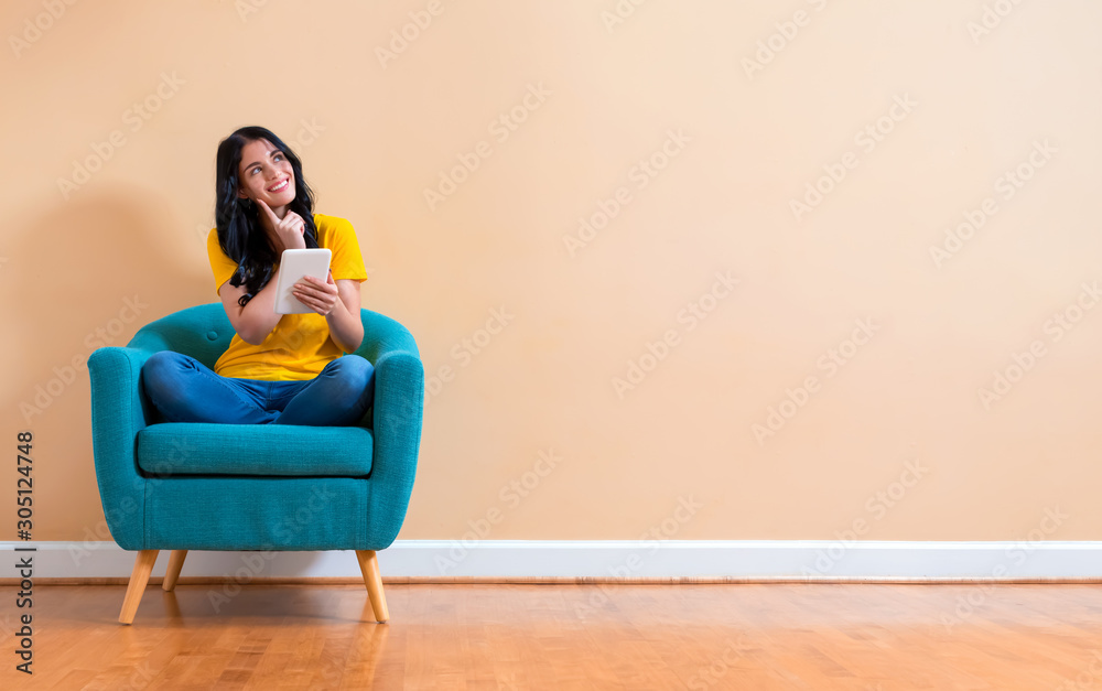 Young woman using her tablet sitting in a chair