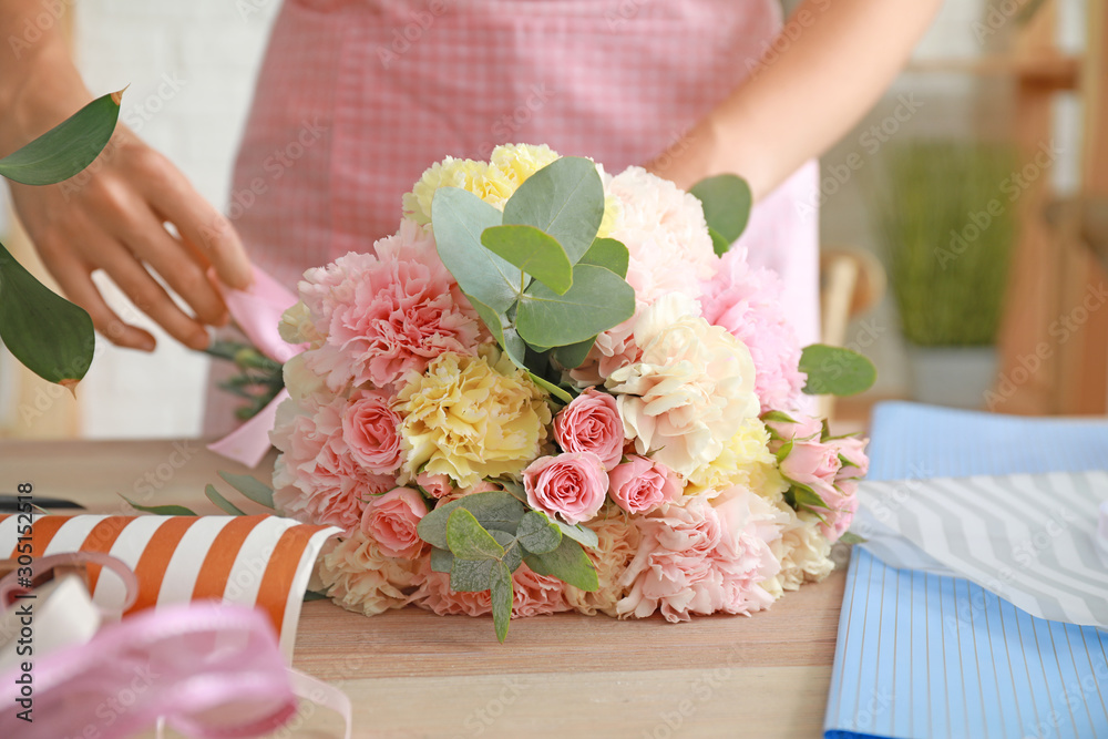 Female florist making beautiful bouquet in shop, closeup