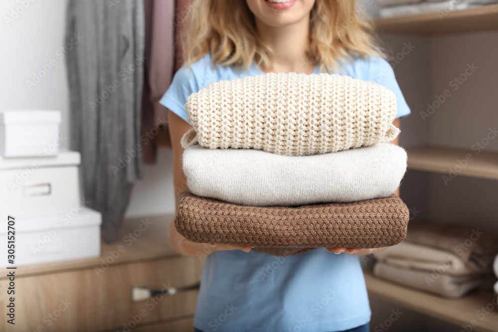 Woman with stack of clean clothes at home, closeup