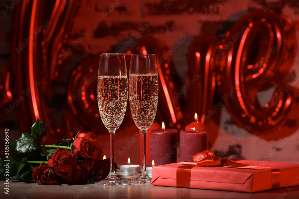 Glasses of champagne, flowers and gift for Valentines Day on table