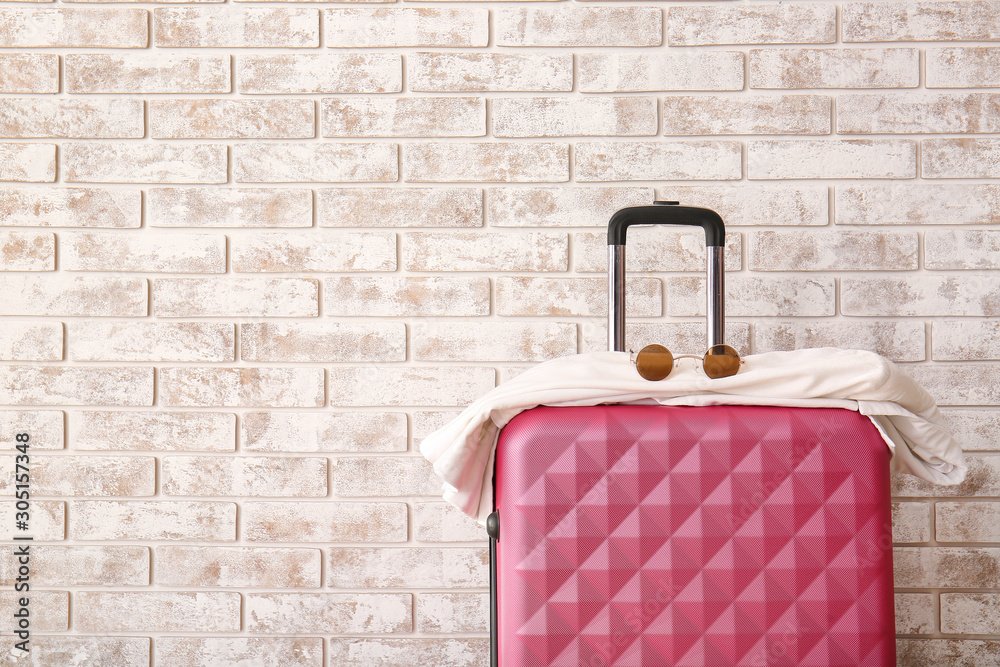 Suitcase near brick wall. Travel concept