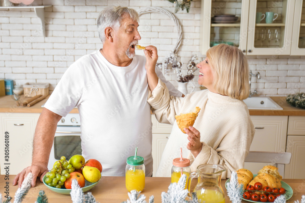 Happy mature couple having breakfast in kitchen