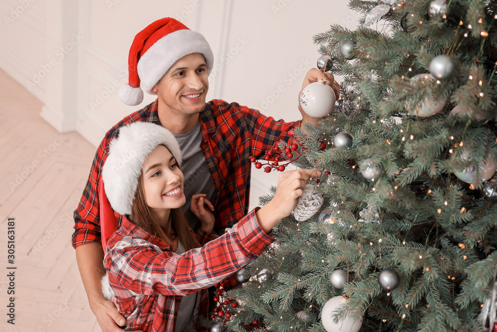 Happy couple decorating Christmas tree at home