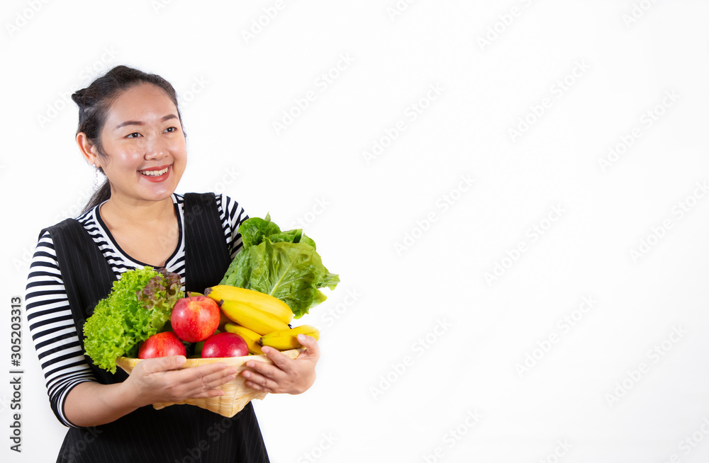 一位美丽的亚洲女性穿着白色连衣裙，拿着健康的水果和蔬菜节食的形象