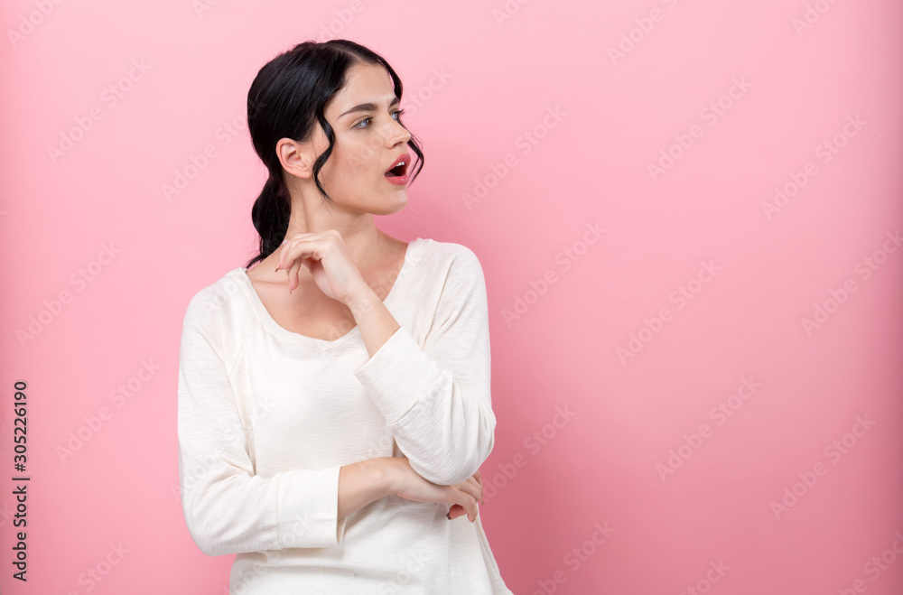 Surprised young woman posing on a pink background