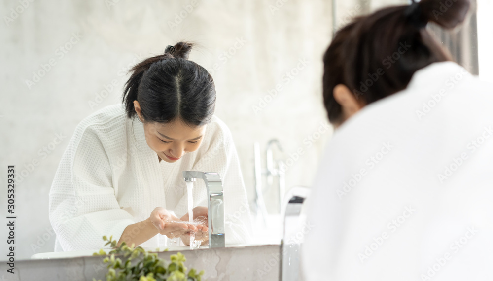 年轻的亚洲女人在浴室里洗脸。