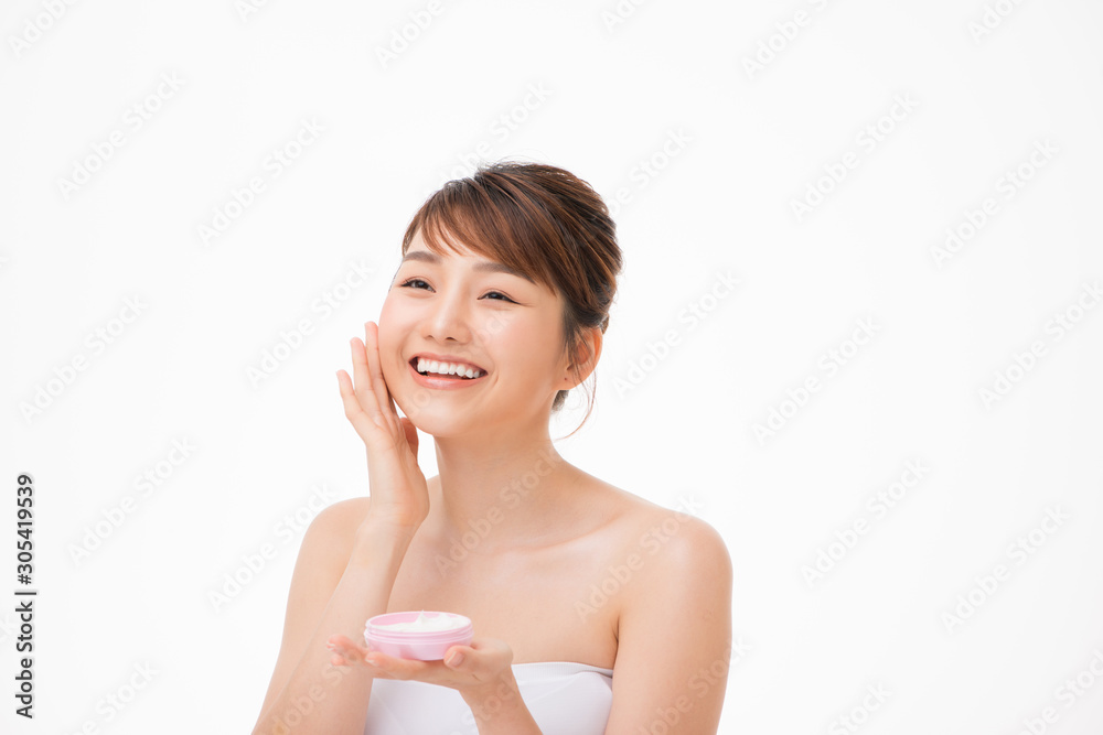 Beauty concept. Asian girl is applying cream on her face.