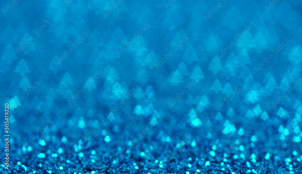 Blue holiday glitter background with Christmas tree bokeh.