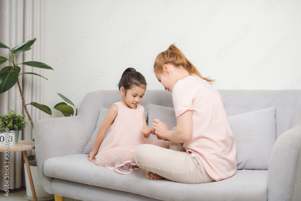 mom using pink nail polish to paint her cute daughters nail to make her happier and prettier