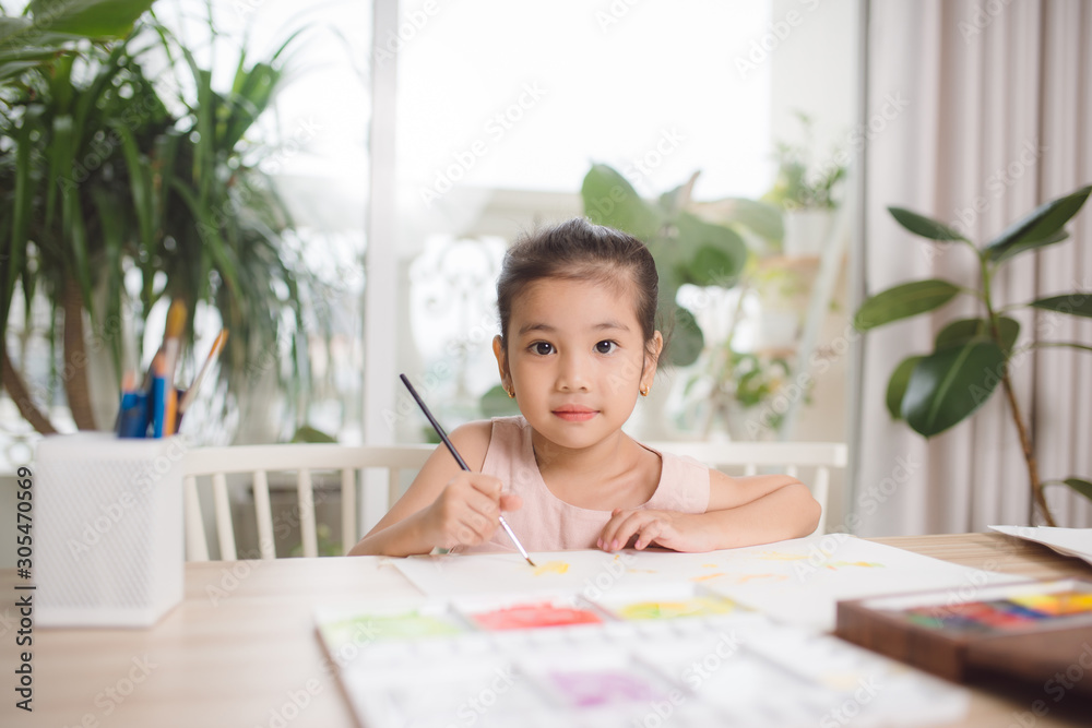 Cute little girl painting picture on home interior background