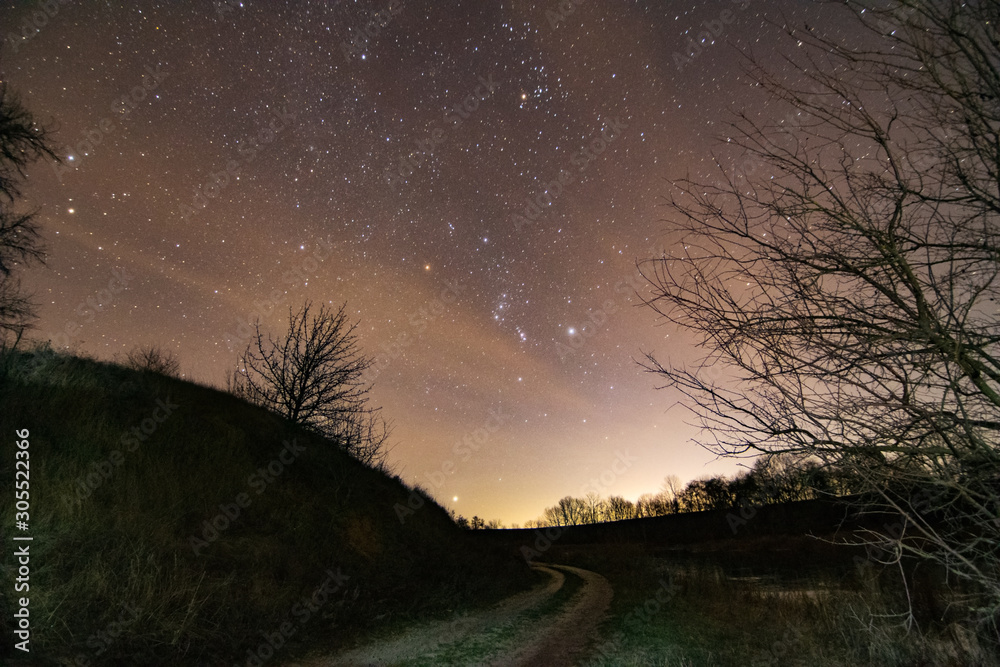 秋天的夜空，地平线上的猎户座升起。星星和路