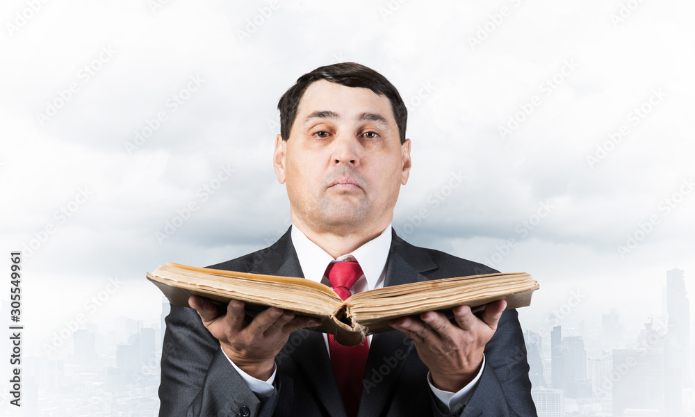 Serious businessman holding open old book