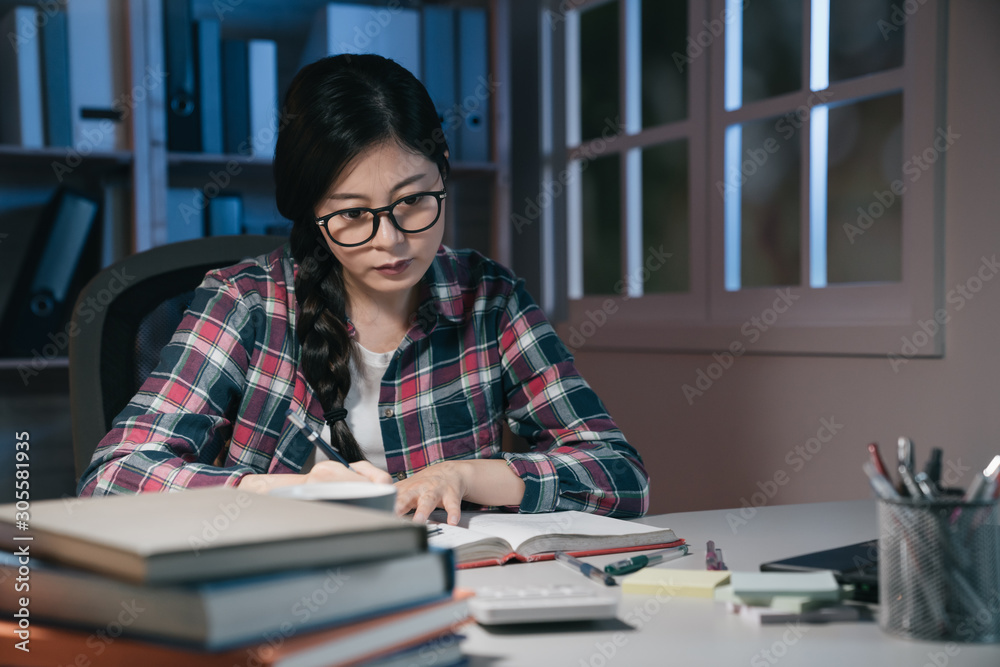 Young asian chinese woman in eyeglasses studying late at night at home. hard working girl student re