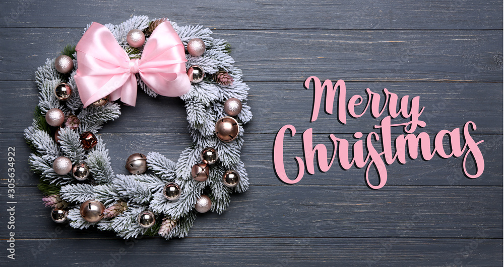 Beautiful wreath and text MERRY CHRISTMAS on wooden background