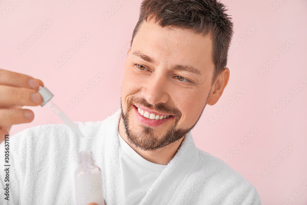 Handsome man with cosmetic product on color background