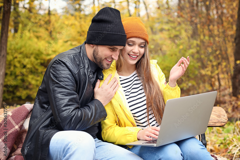 Loving young couple with laptop in autumn park