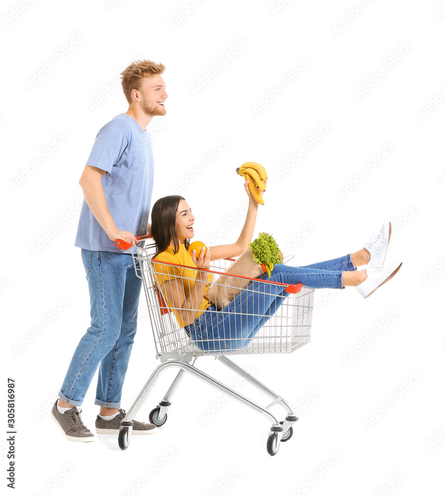 Young couple with shopping cart on white background