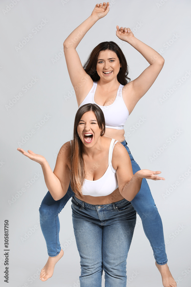 Young body positive women on grey background