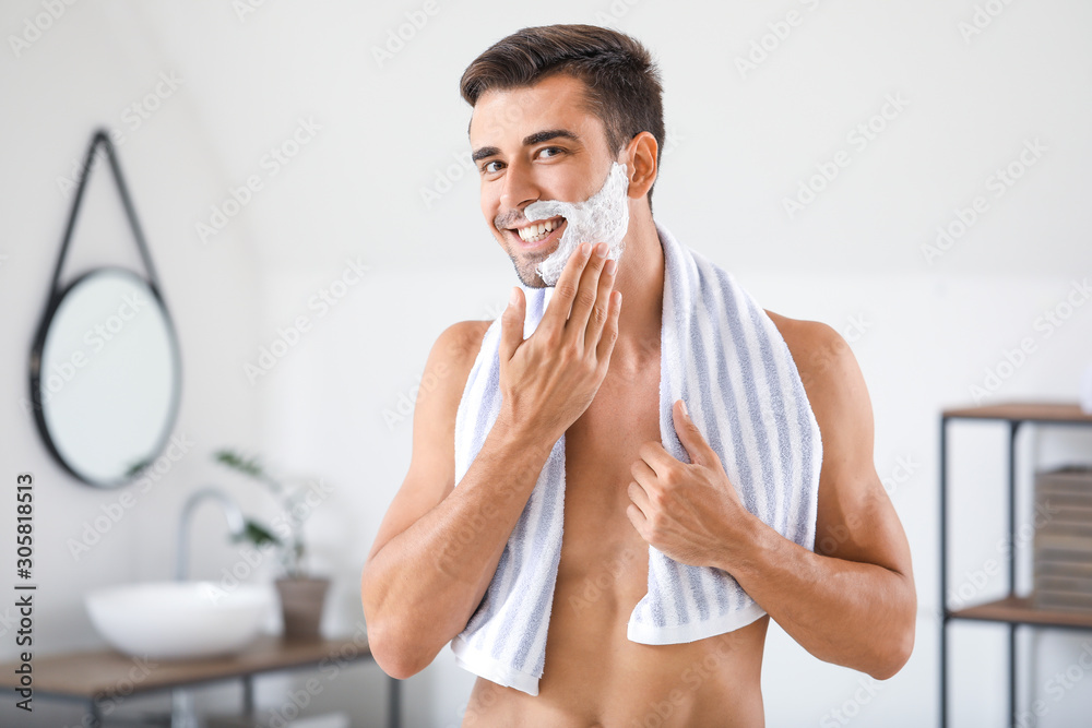 Handsome young man shaving at home