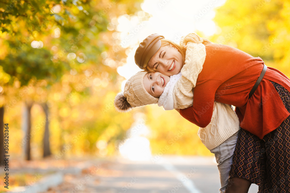 Portrait of happy mother and little daughter in autumn park