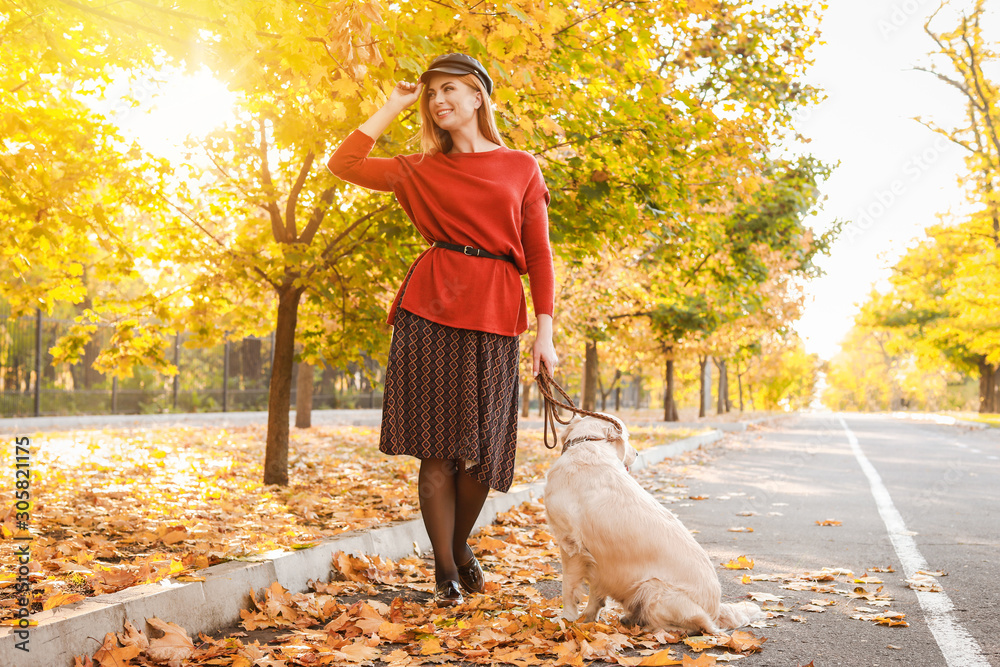 Young woman walking with dog in autumn park