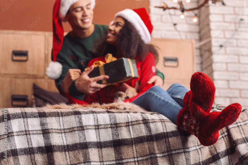 Happy African-American couple with Christmas gift at home