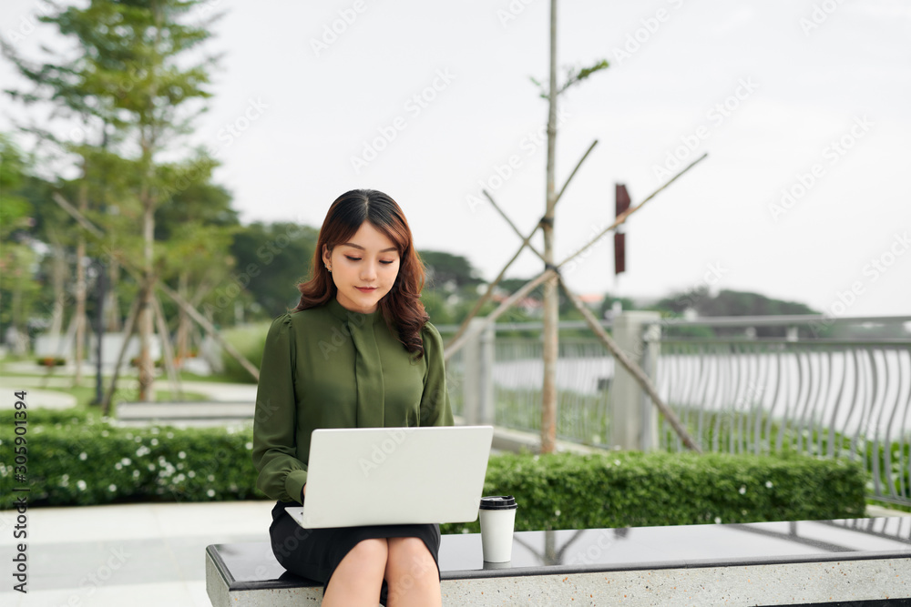 忙碌的销售女性坐在商业园区用笔记本电脑在暴徒身上写文字的肖像