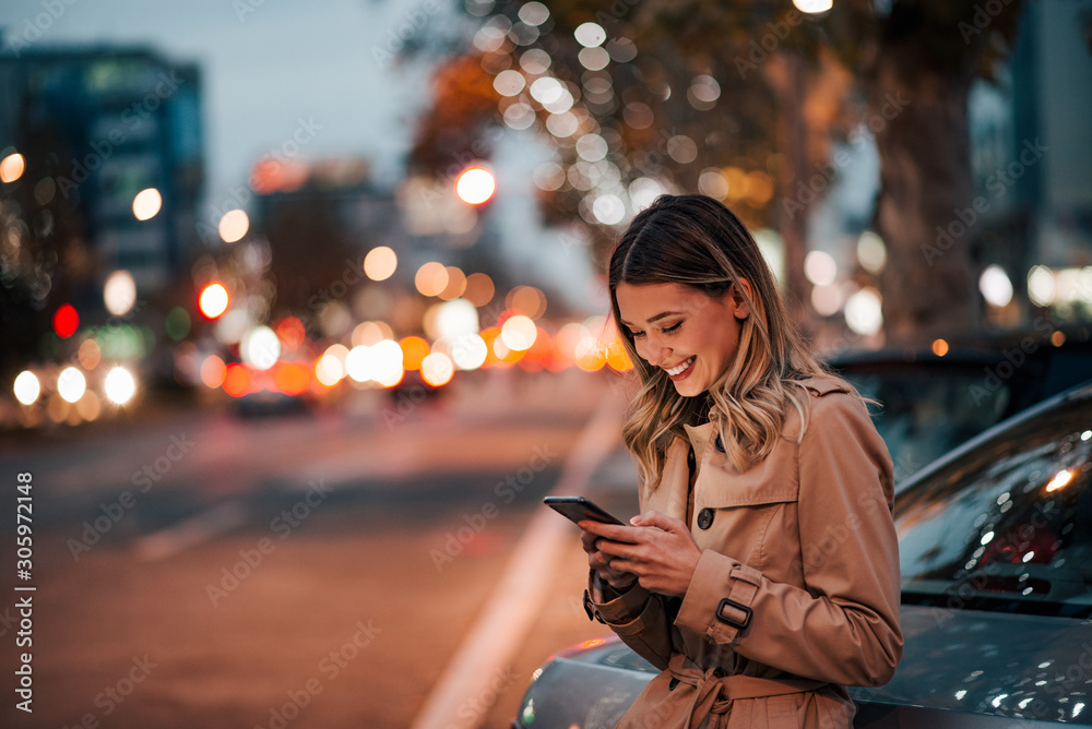 City, technology and people. Cute cheerful girl using phone in the city street.