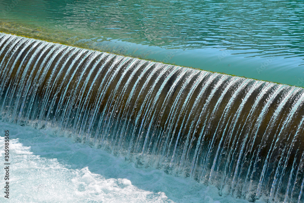 Blue river water falling from rift with foam