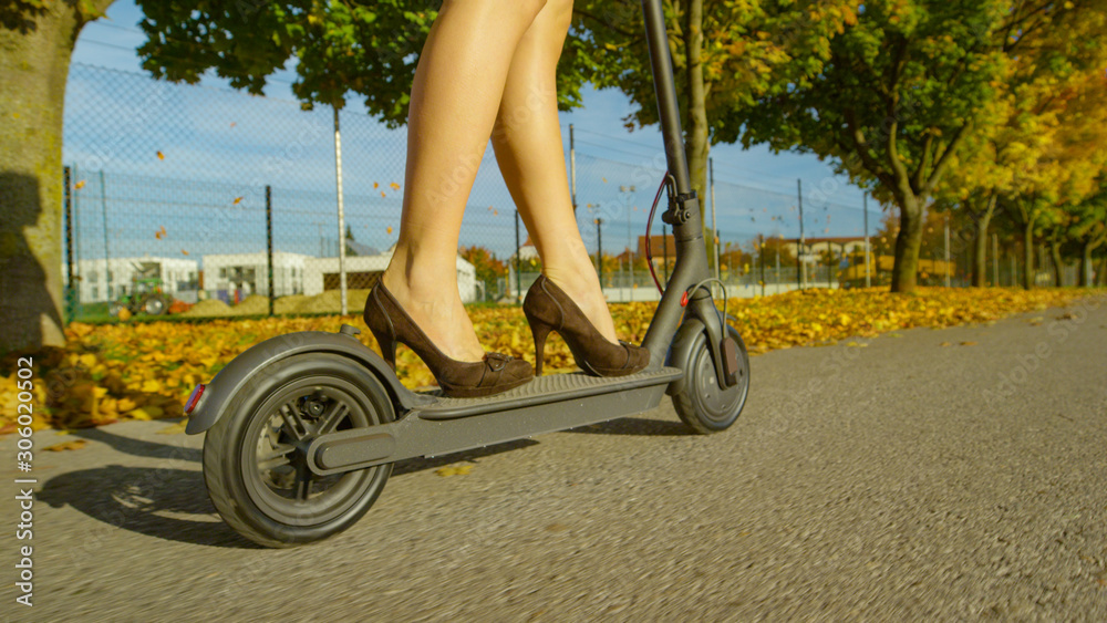 CLOSE UP: Young businesswoman commutes to work on a cool electric scooter.