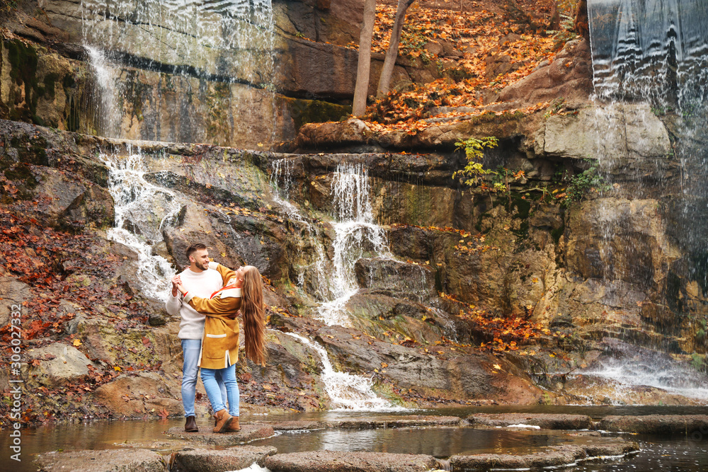 Loving young couple near waterfall