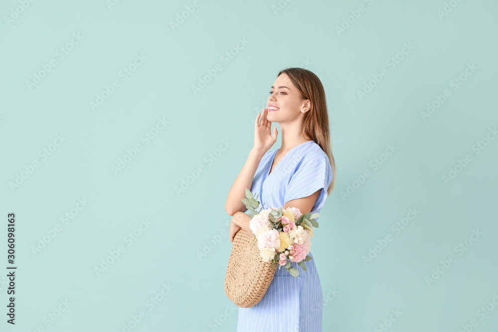 Beautiful young woman with bag and bouquet of carnation flowers on color background