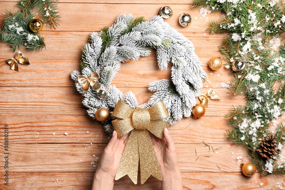 Woman making beautiful Christmas wreath on wooden background