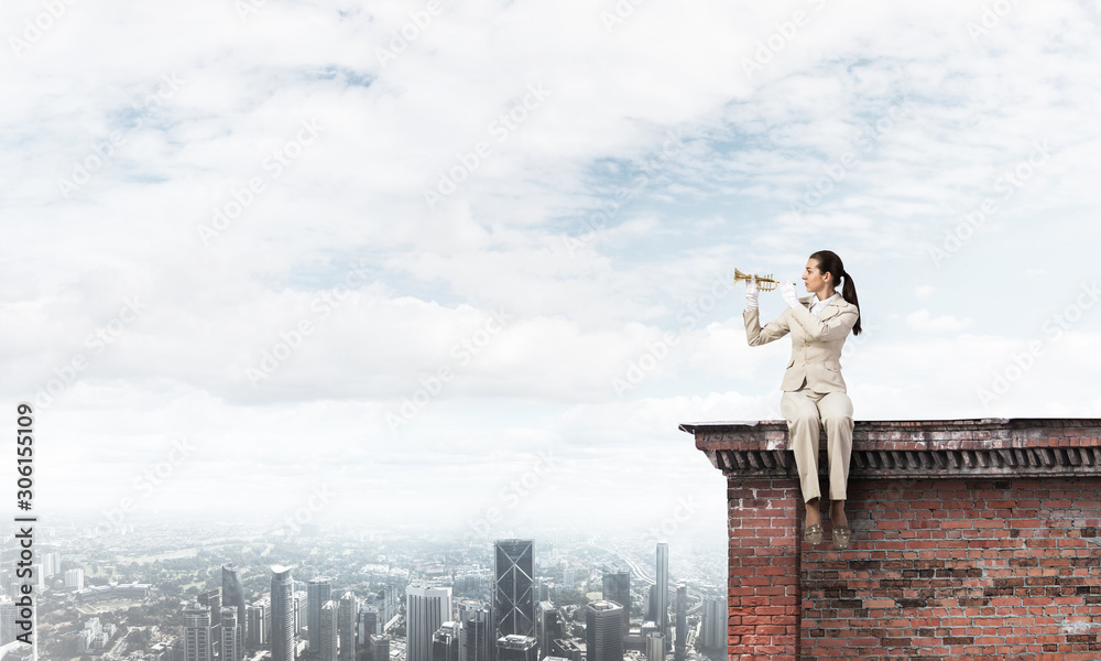 Attractive young woman playing trumpet on roof