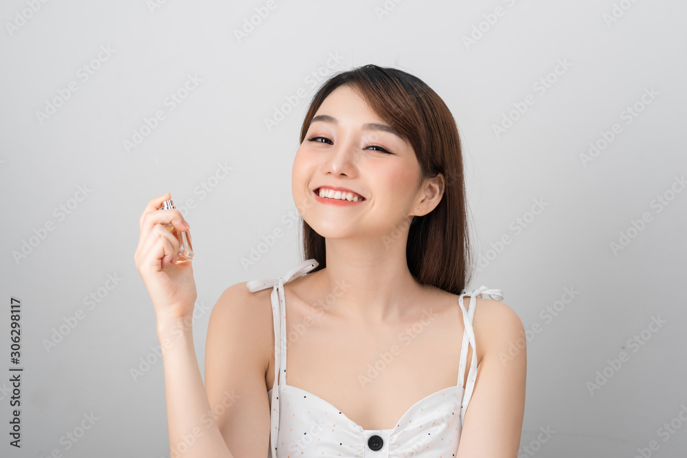 A beautiful woman of Asian appearance smiles into the camera and holds in her hand a jar of liquid w