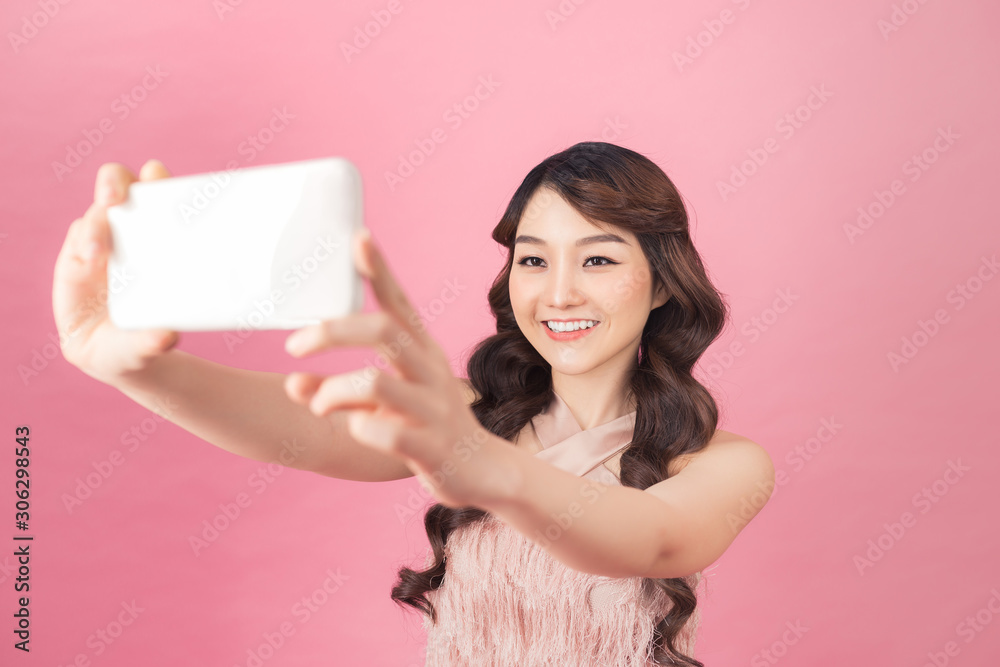 Studio portrait of beautiful woman smiling with white teeth and making selfie, photographing herself