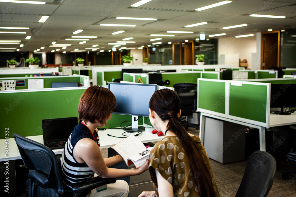 雑誌を一緒に読む女性社員達