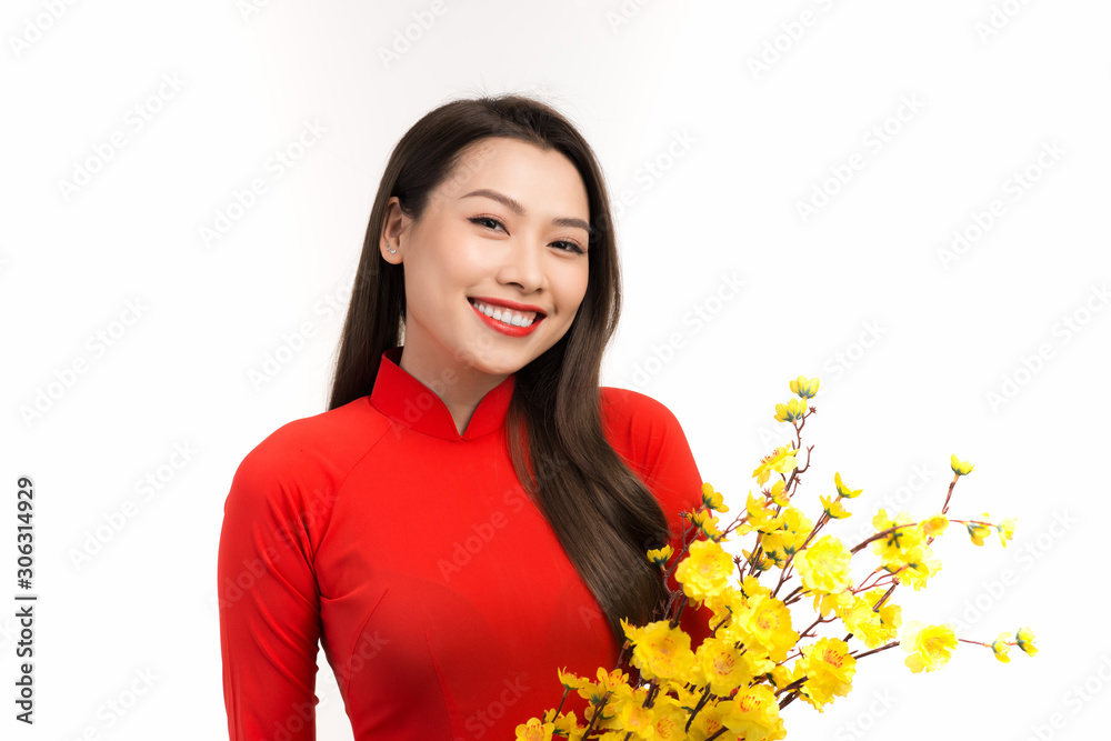 Beauty woman in Vietnamese traditional dress ao dai, apricot blossom in Lunar New year.