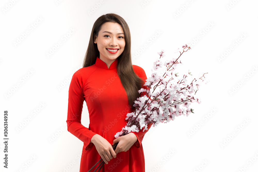 Asian woman with vietnamese traditional dress ao dai holding peach blossom flower for decorations