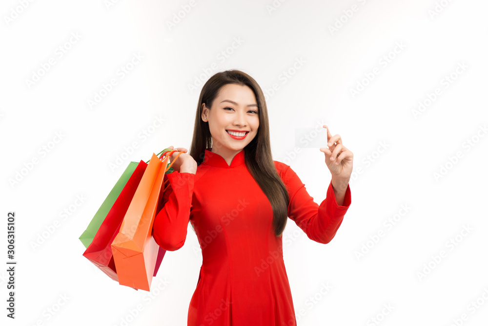 Beautiful asian girl wearing vietnamese traditional dress carrying many paper shopping bags and smar