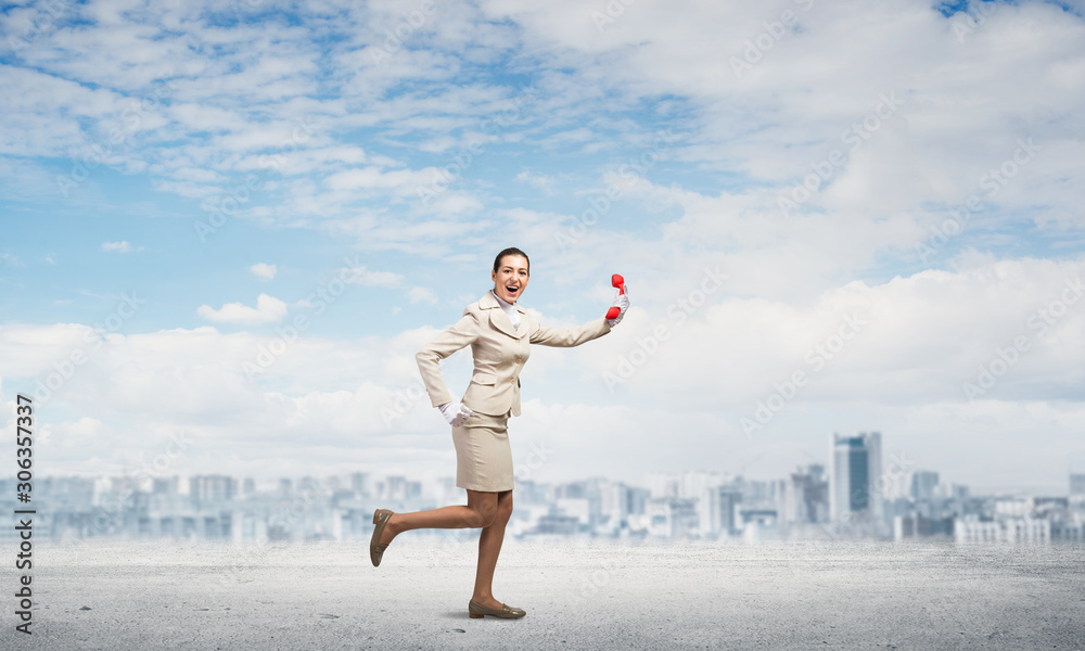 Woman running outdoor with vintage red phone