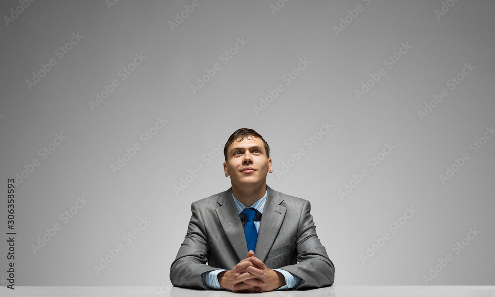 Smiling man folded hands and looking upward.