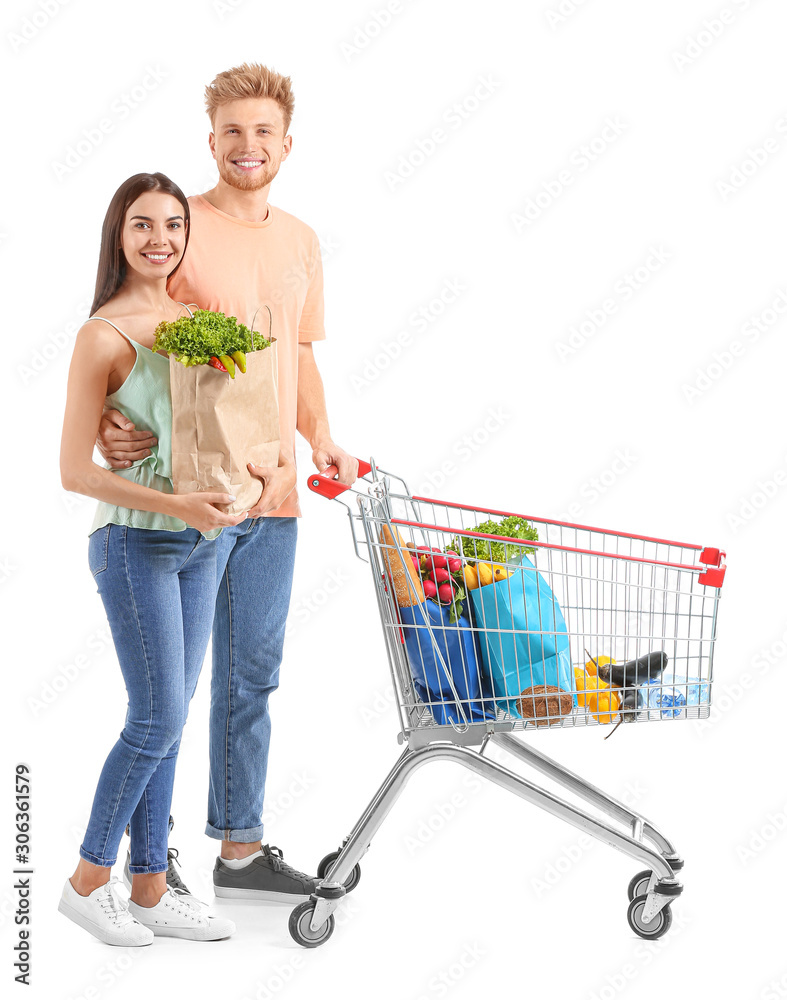 Young couple with shopping cart on white background