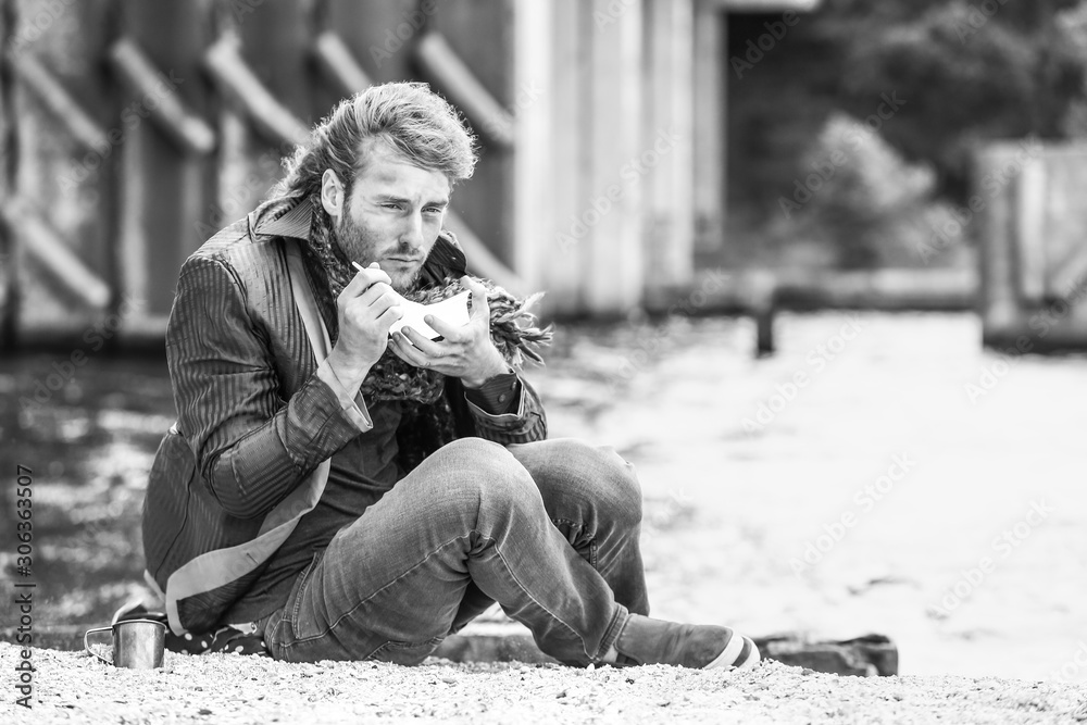 Black and white portrait of poor homeless man eating food outdoors