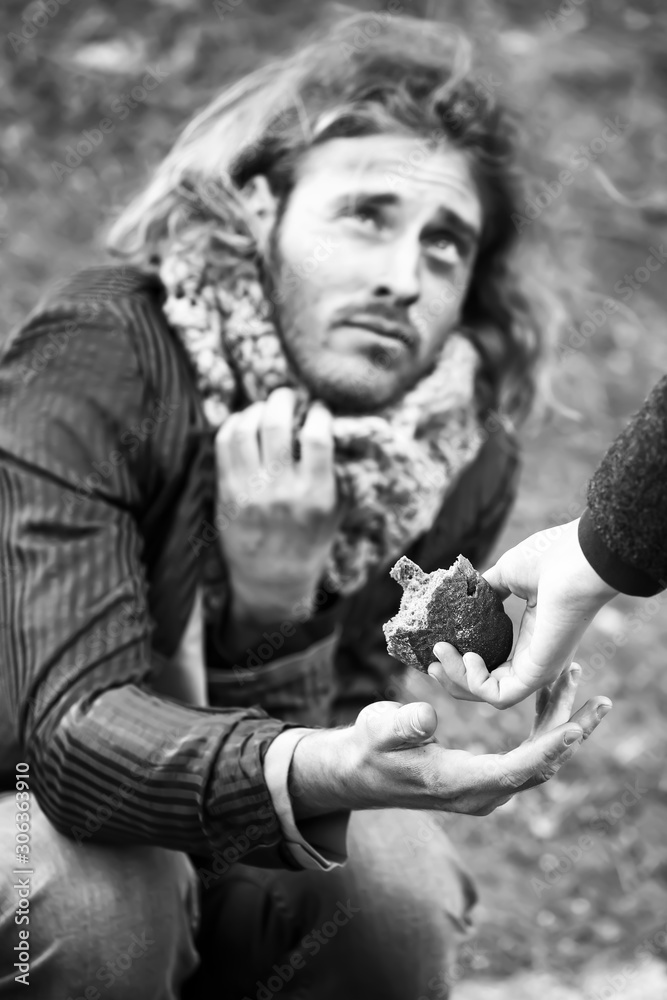 Woman giving bread to poor homeless man outdoors